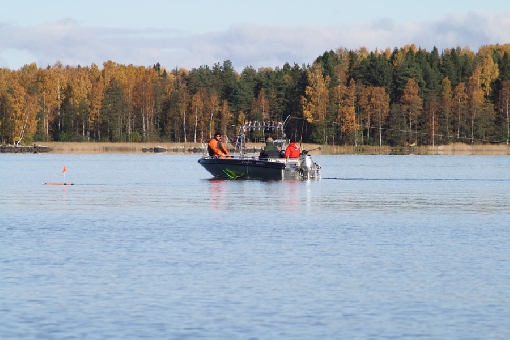 El pescador a remolque de salmónidos se aventura en aguas profundas en el centro de lago abierto de Roine.